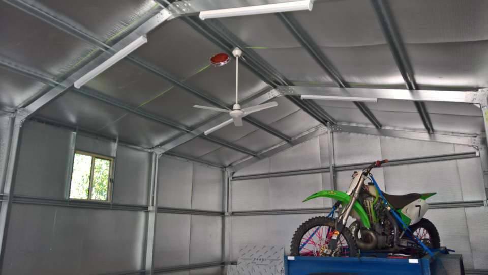 A Motorcycle Is Parked In A Garage With A Ceiling Fan — Alice Sheds & Structures In Ciccone, NT