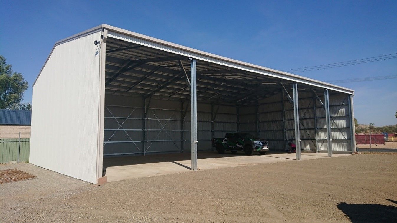 A Large White Building With A Car Parked Inside Of It — Alice Sheds & Structures In Ciccone, NT