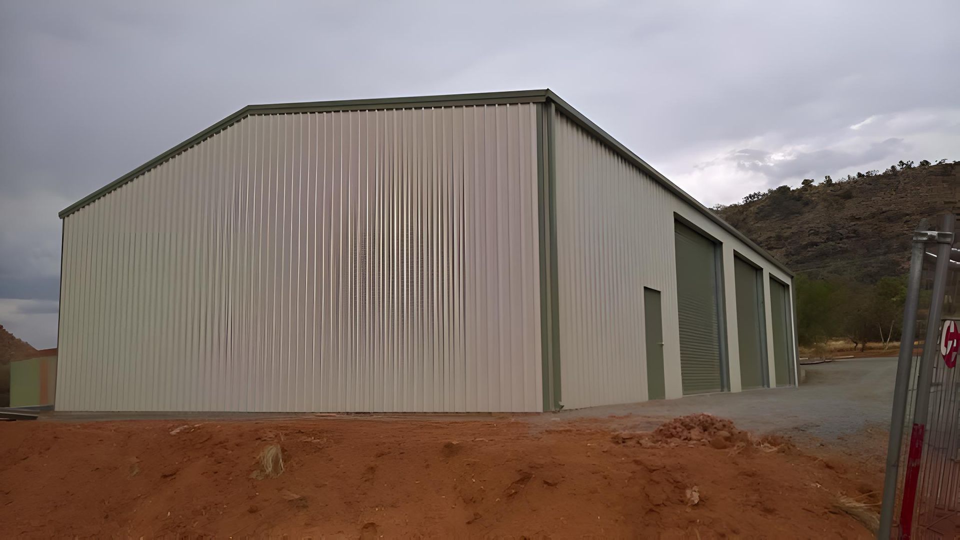 A Large Metal Building Is Sitting On Top Of A Dirt Hill — Alice Sheds & Structures In Ciccone, NT