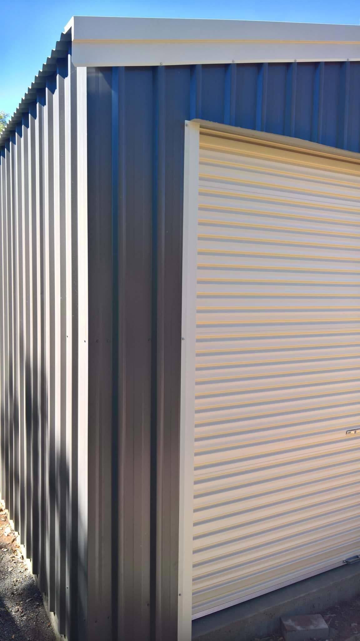 A Close Up Of A Metal Building With A Garage Door — Alice Sheds & Structures In Ciccone, NT