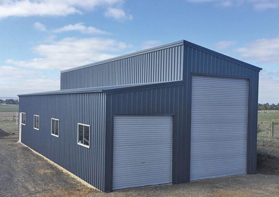 A Large Metal Building With A Garage Door And Windows — Alice Sheds & Structures In Ciccone, NT