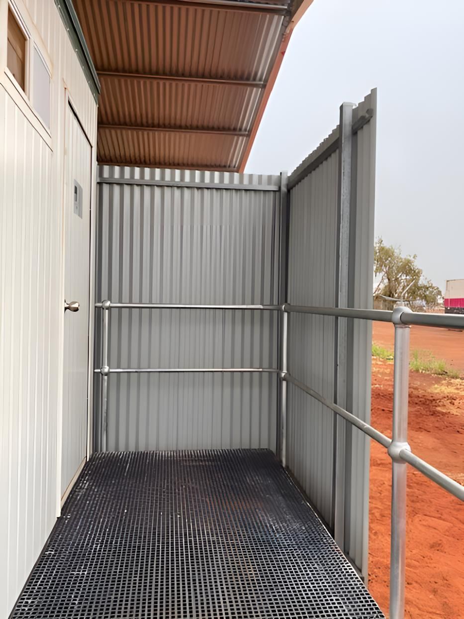 A White Building With A Metal Fence And Stairs Leading To It — Alice Sheds & Structures In Ciccone, NT