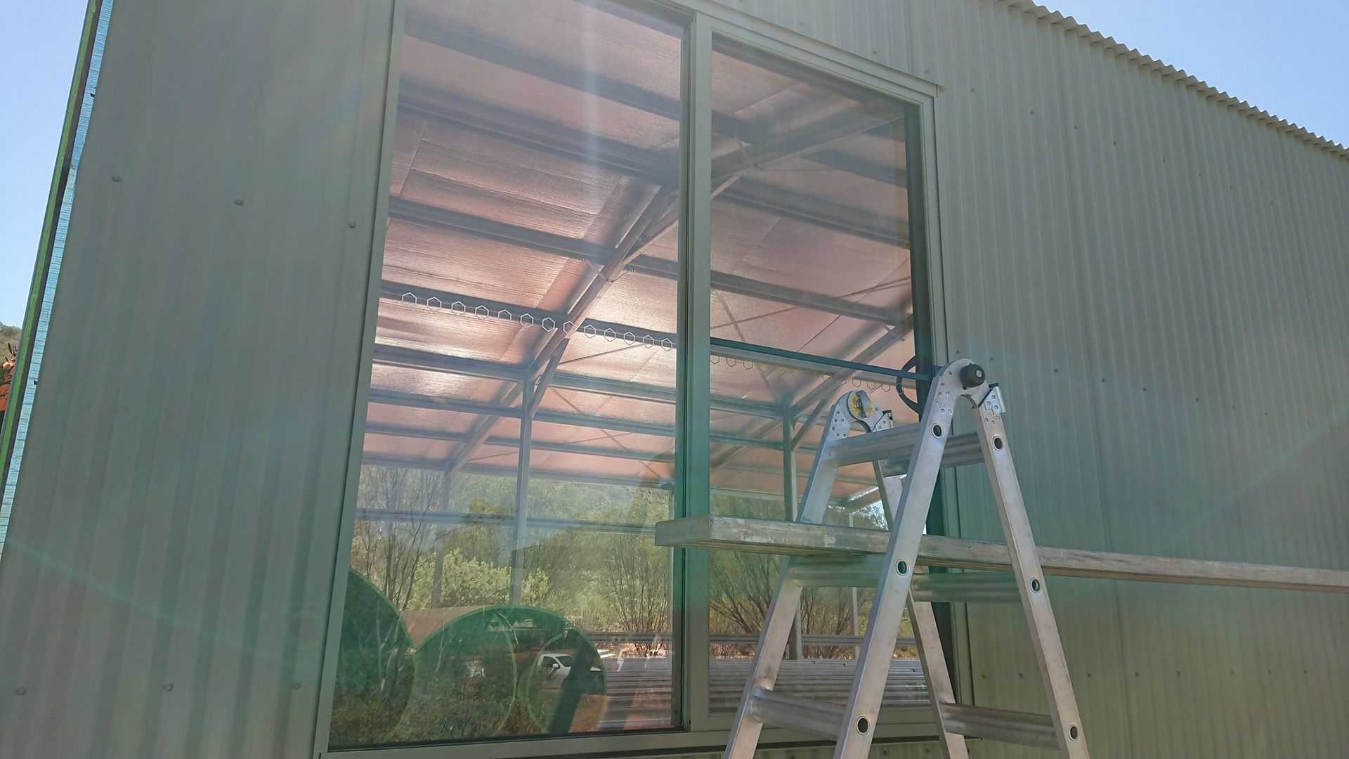 A Grey Shed With A Ladder In Front Of A Door — Alice Sheds & Structures In Ciccone, NT