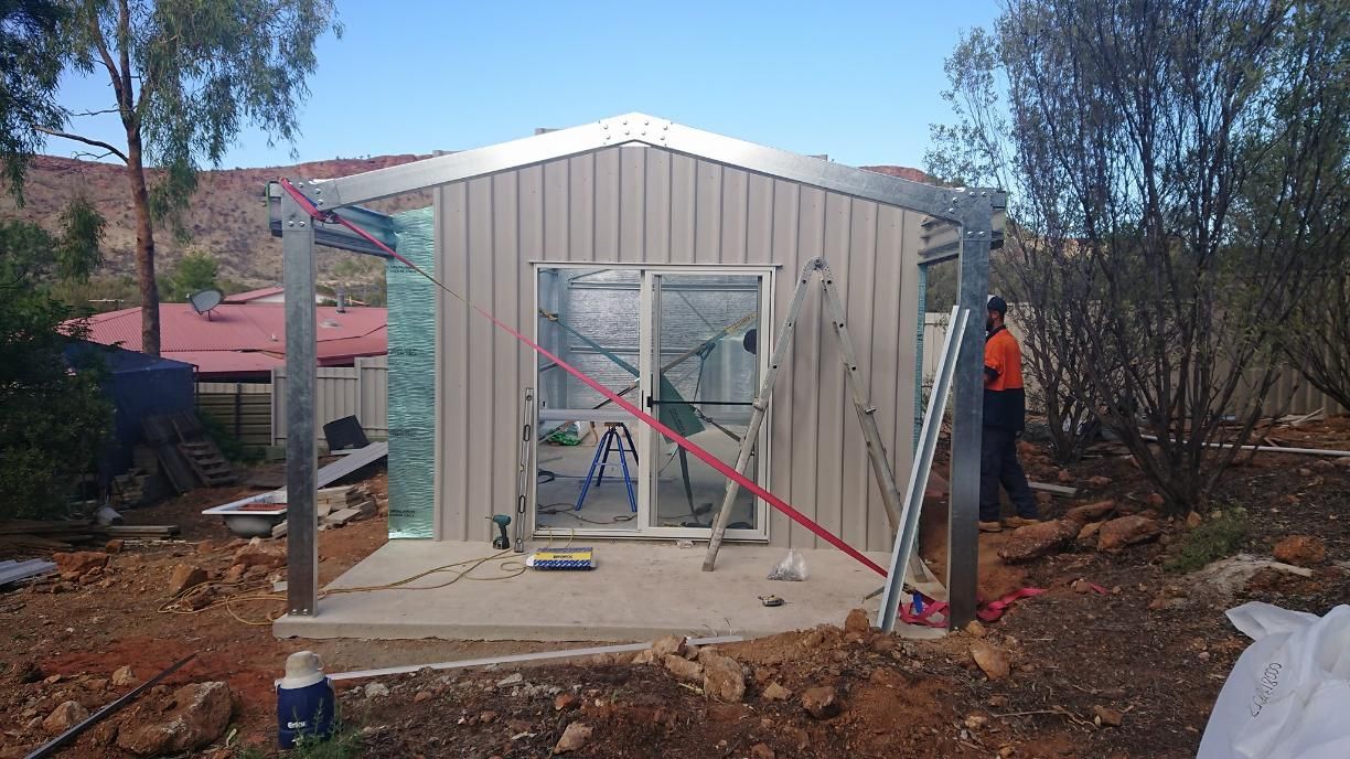A Man Is Standing In Front Of A Building That Is Being Built — Alice Sheds & Structures In Ciccone, NT