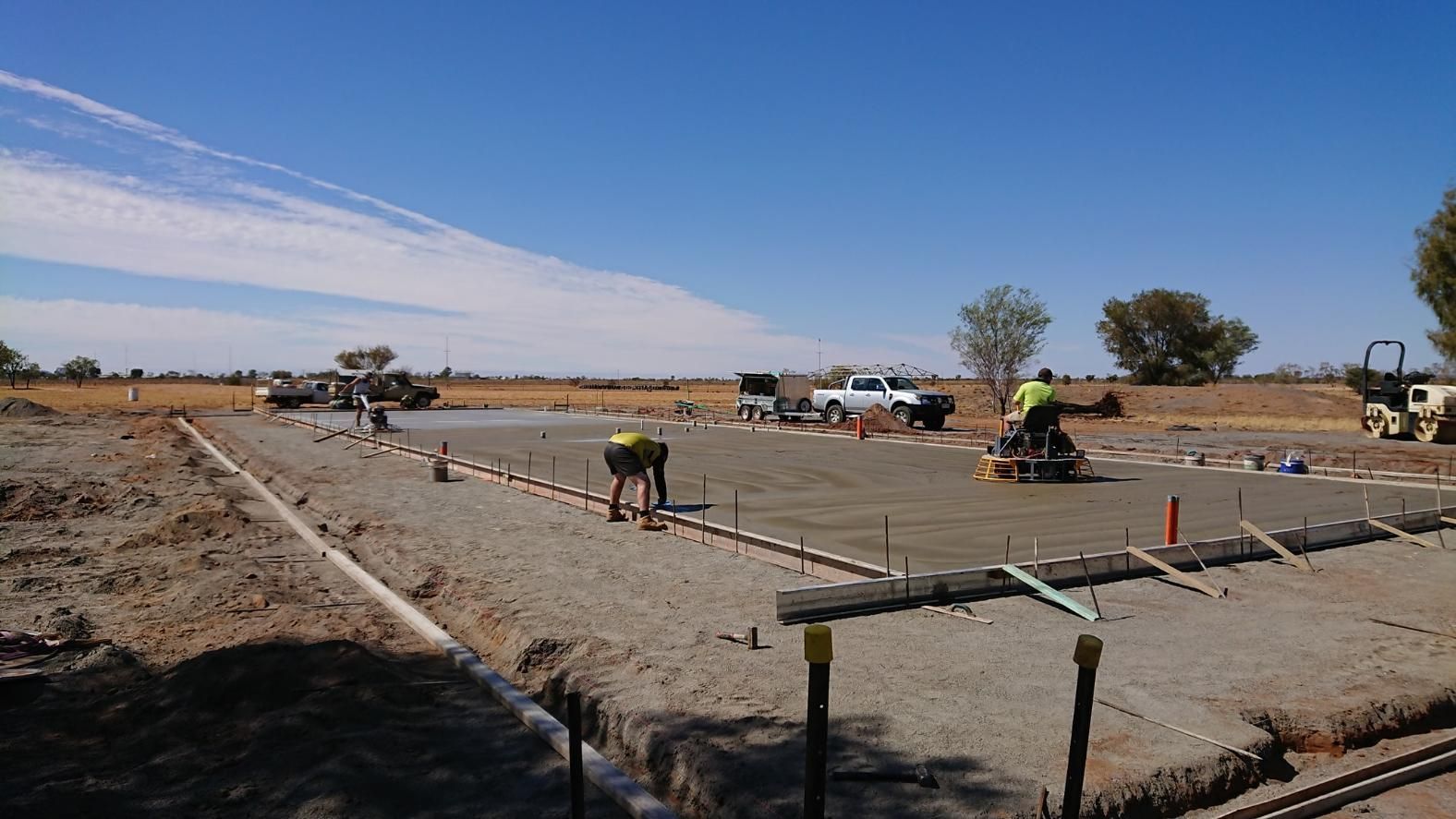 A group of construction workers are working on a concrete driveway — Alice Sheds & Structures In Ciccone, NT