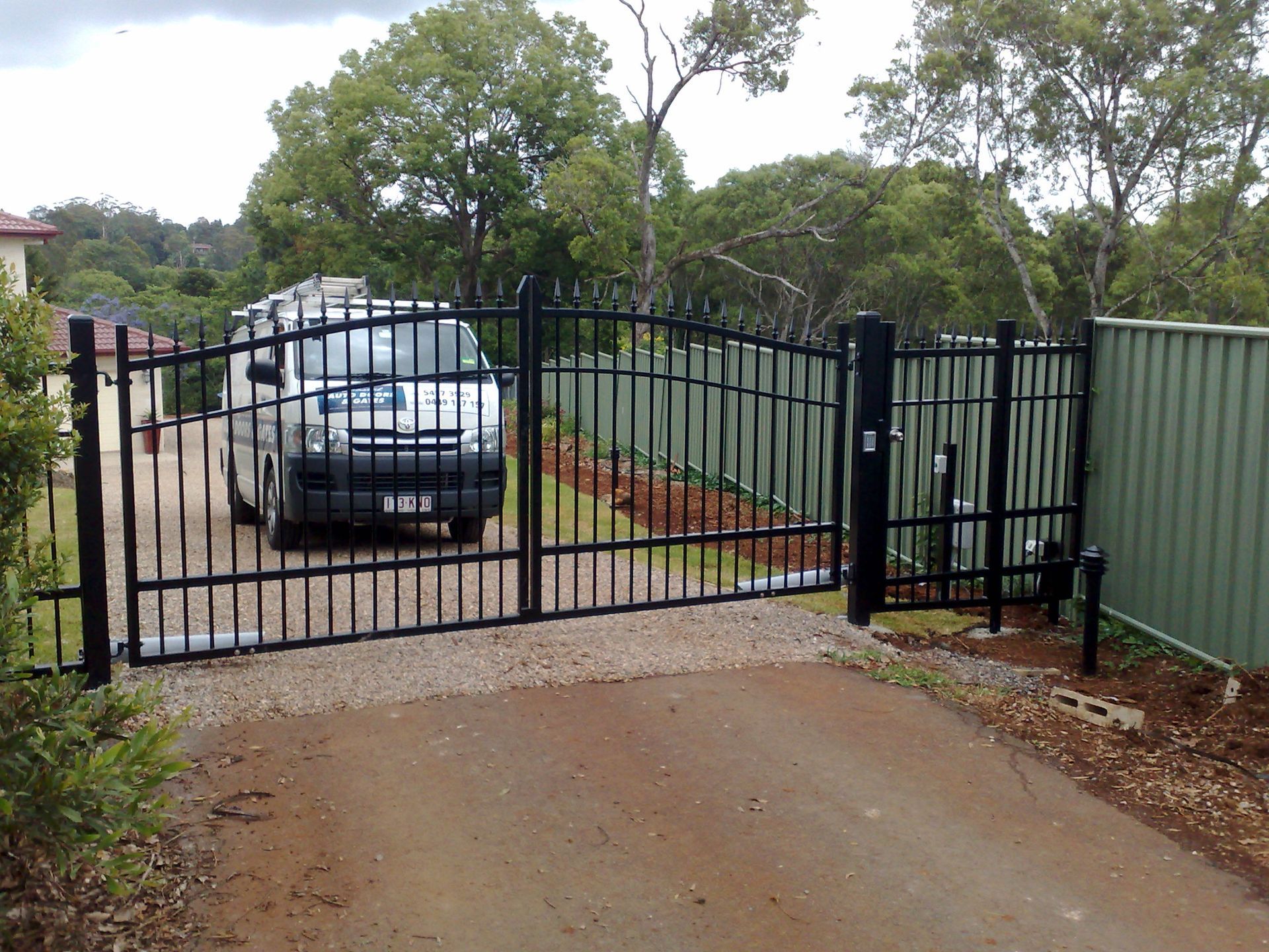 Black Metal Driveway Gate, Open, With a Van Parked Inside — Coastal Auto Doors & Gates In Caloundra, QLD