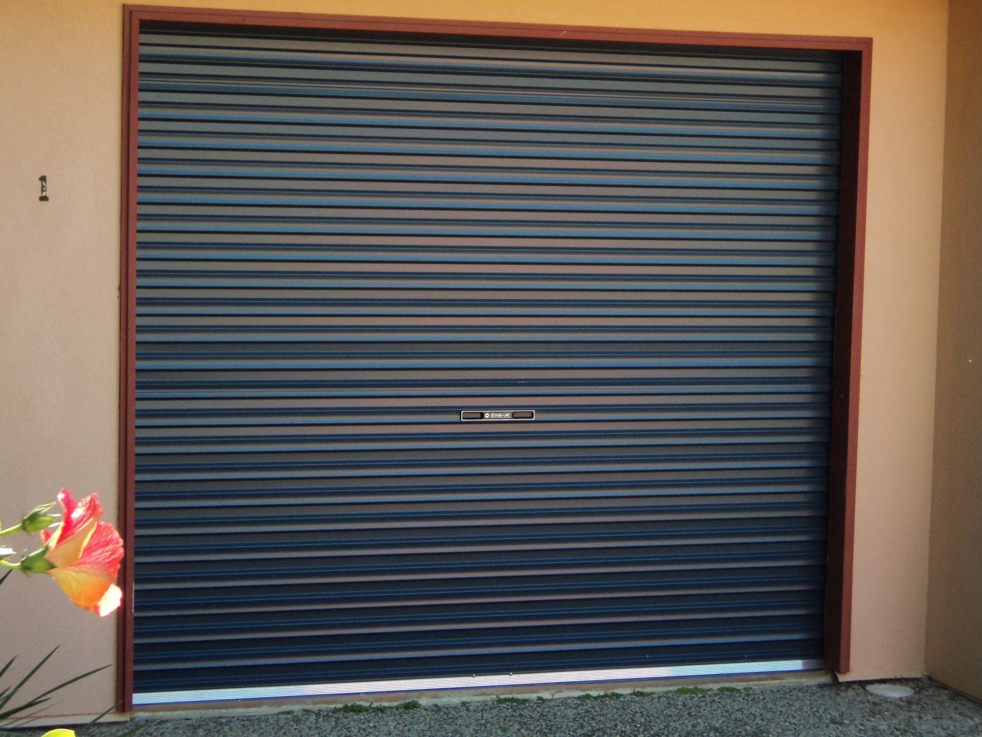 Closed Dark Blue Roller Garage Door With a Brown Frame — Coastal Auto Doors & Gates In Sunshine Coast, QLD