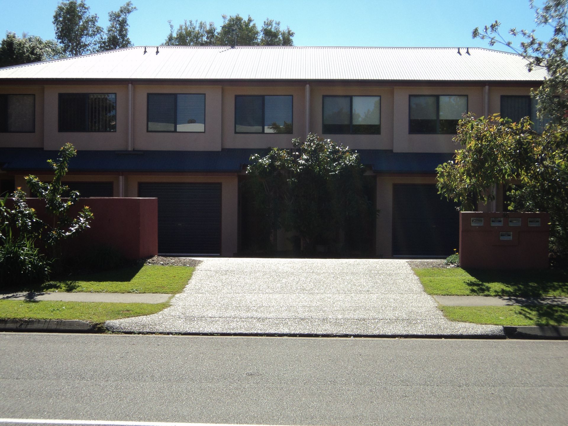 Townhouses With Light Pink Exterior, Dark Garages, and a Concrete Driveway — Coastal Auto Doors & Gates In Maroochydore, QLD
