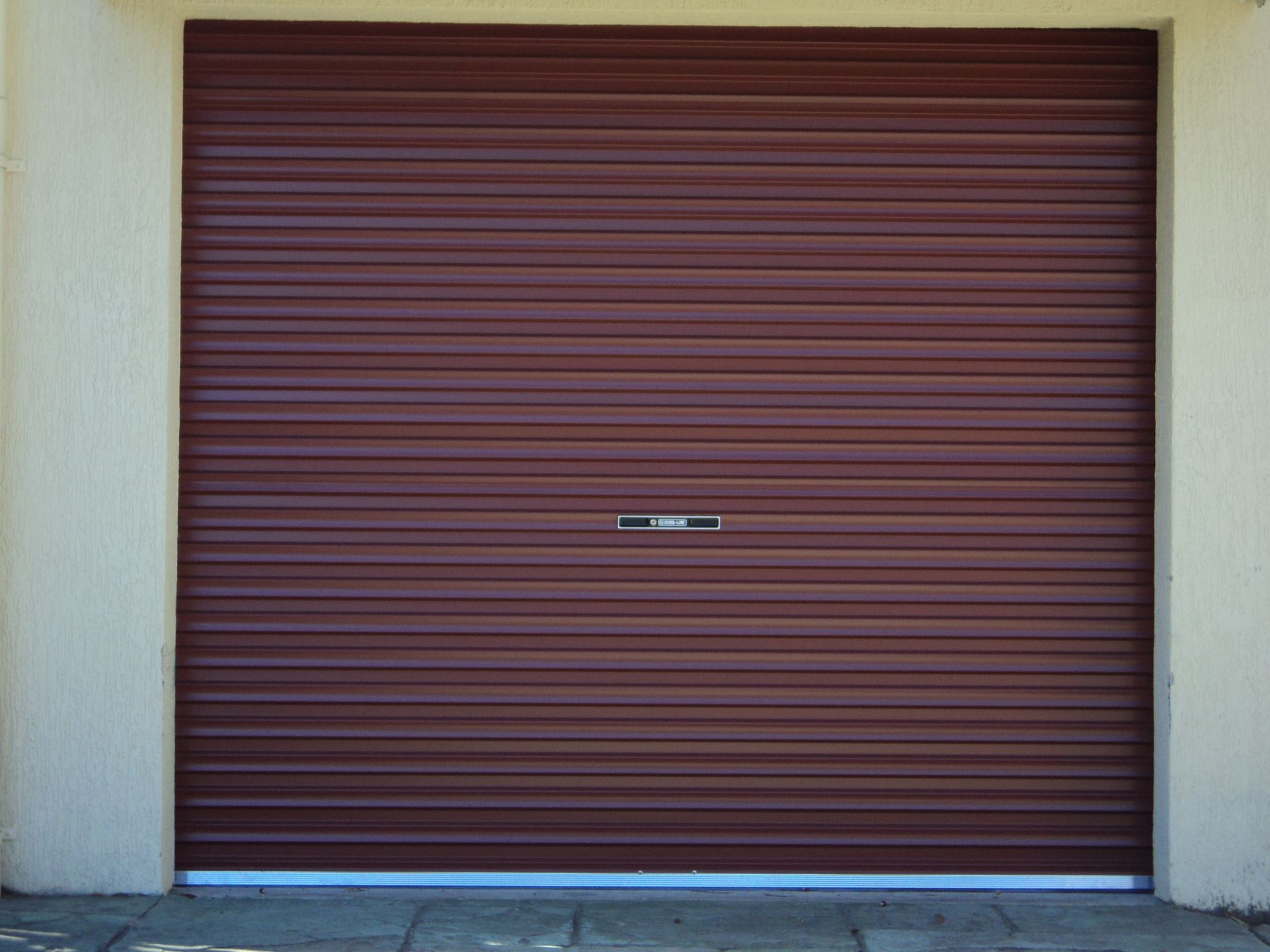 Brown Rolling Garage Door, Closed, Set in a White and Cream Frame — Coastal Auto Doors & Gates In Palmwoods, QLD