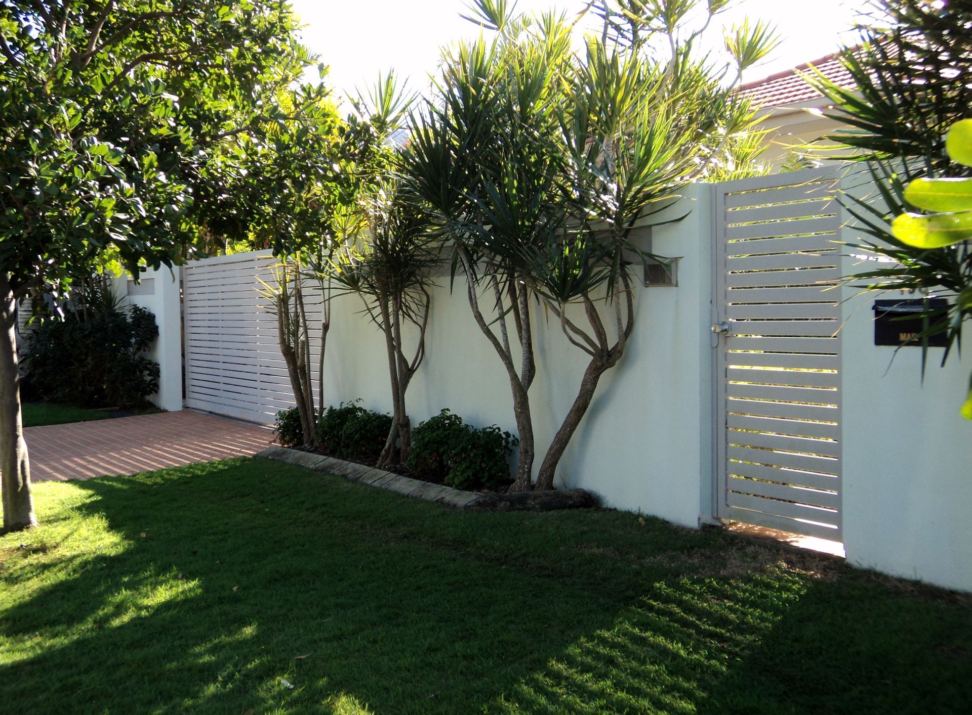 White Slatted Fence and Gate Alongside a Light-colored Wall — Coastal Auto Doors & Gates In Palmwoods, QLD