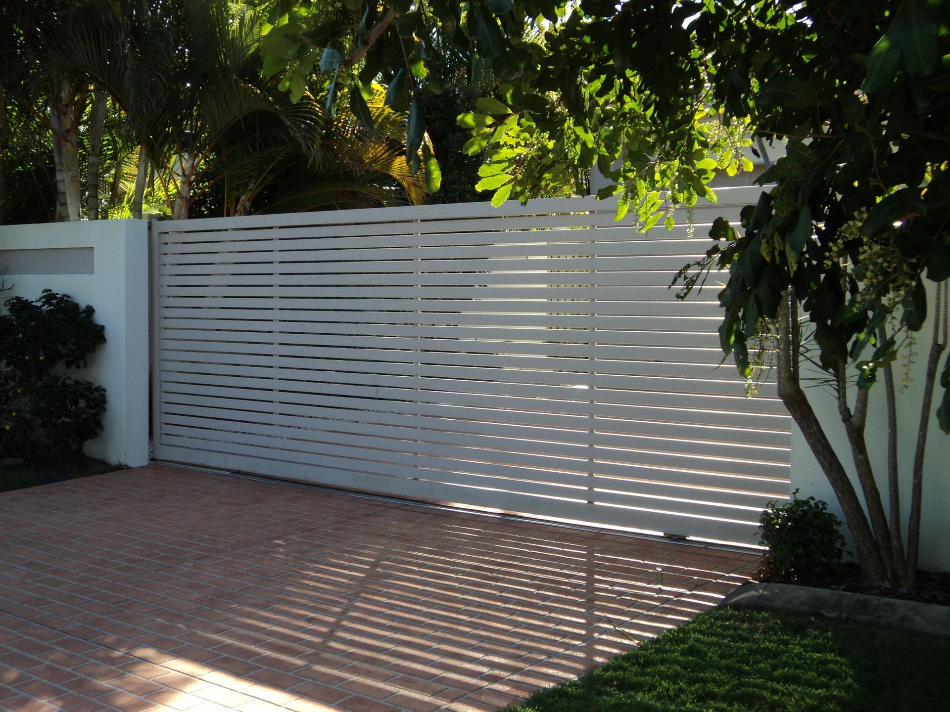 White Horizontal Slat Gate in Front of a Brick Driveway — Coastal Auto Doors & Gates In Palmwoods, QLD