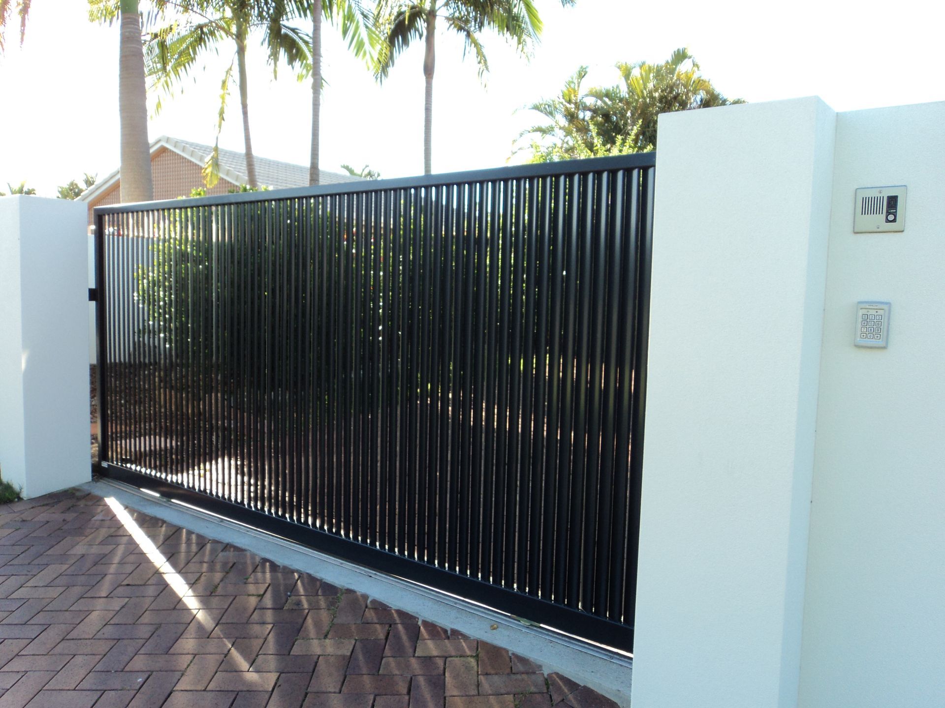 Black Metal Gate With Vertical Bars, White Pillars, Brick Pavement — Coastal Auto Doors & Gates In Sunshine Coast, QLD