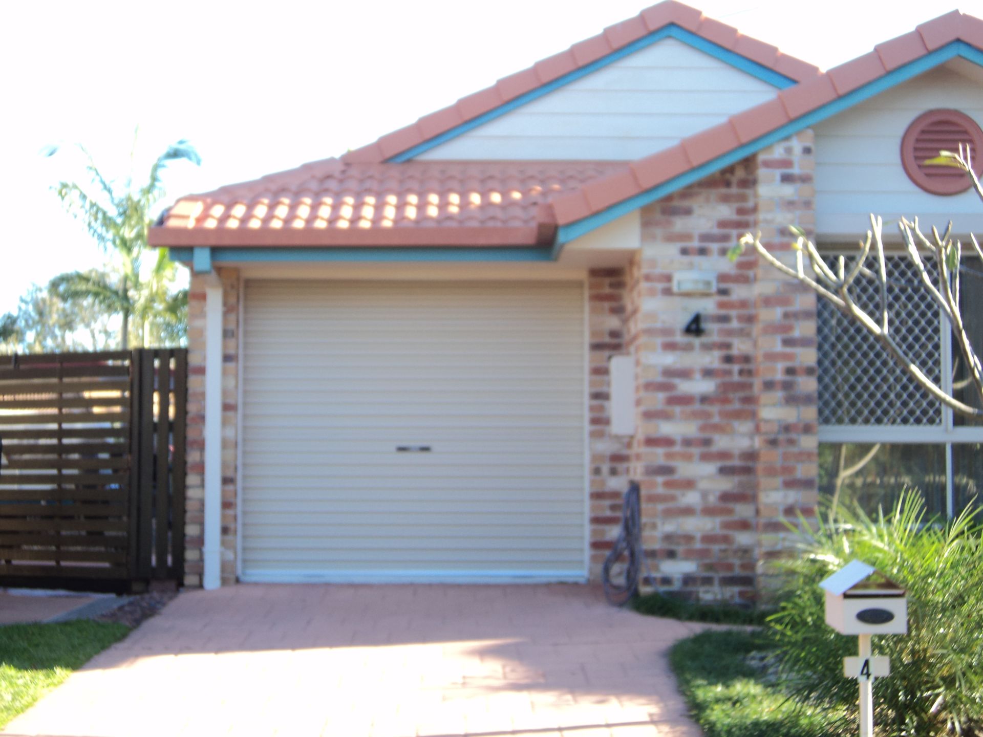 Beige Garage Door on a Brick House With a Red-tiled Roof — Coastal Auto Doors & Gates In Palmwoods, QLD