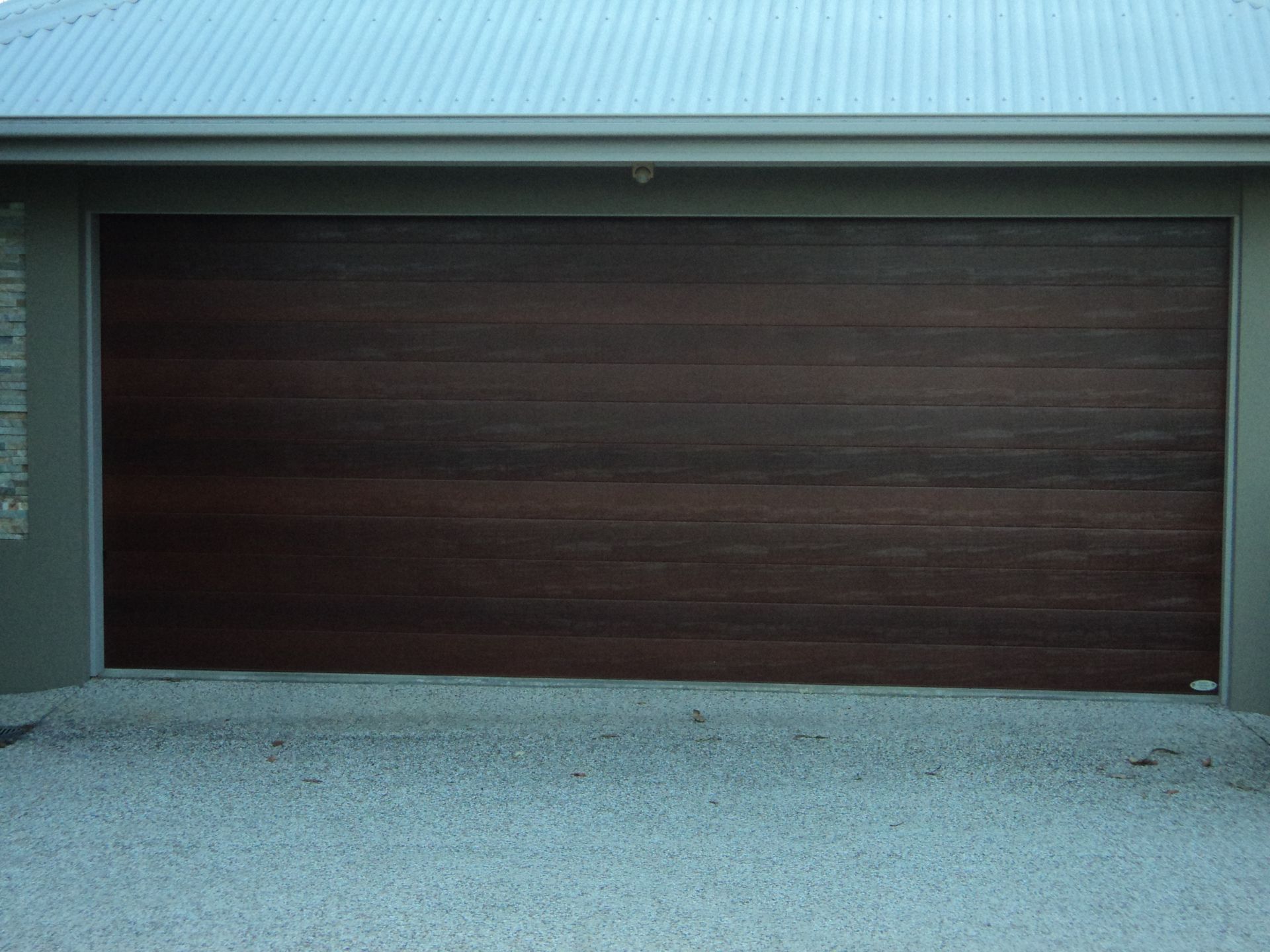 Dark Wood Grain Garage Door Under a Light Gray Roof — Coastal Auto Doors & Gates In Palmwoods, QLD