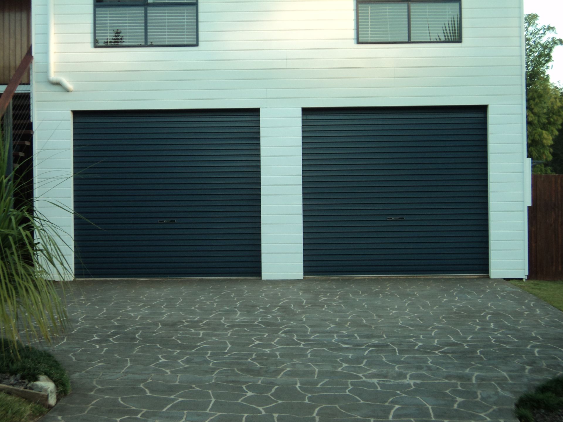 Two-car Garage With Dark Blue Doors and a Patterned Concrete Driveway — Coastal Auto Doors & Gates In Palmwoods, QLD