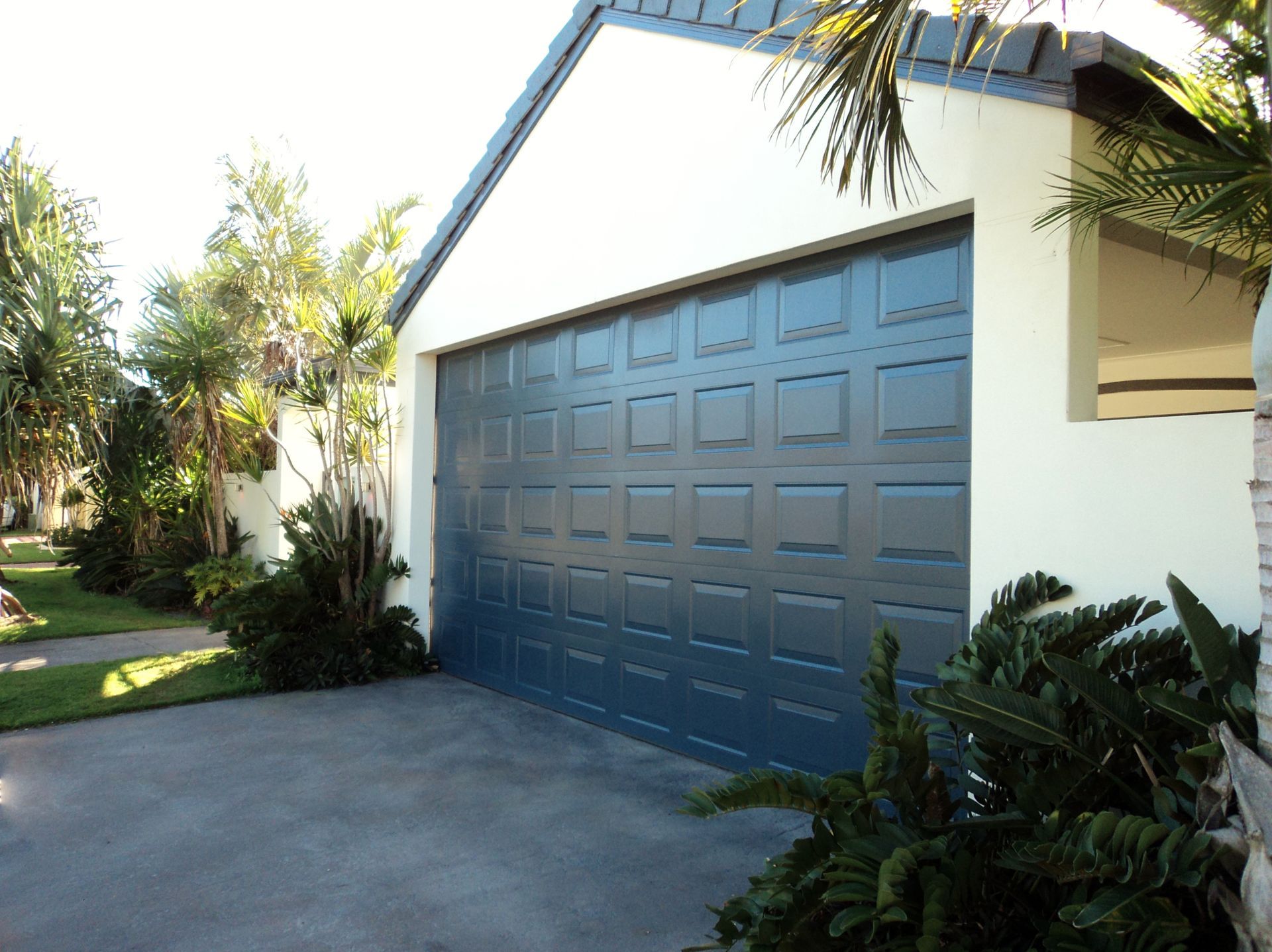 Blue Garage Door on a White House With Landscaping and a Concrete Driveway — Coastal Auto Doors & Gates In Palmwoods, QLD