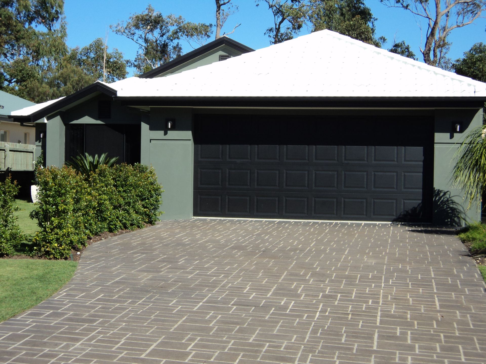 House With a Gray Brick Driveway, Black Garage Door, and Green Exterior Walls — Coastal Auto Doors & Gates In Palmwoods, QLD