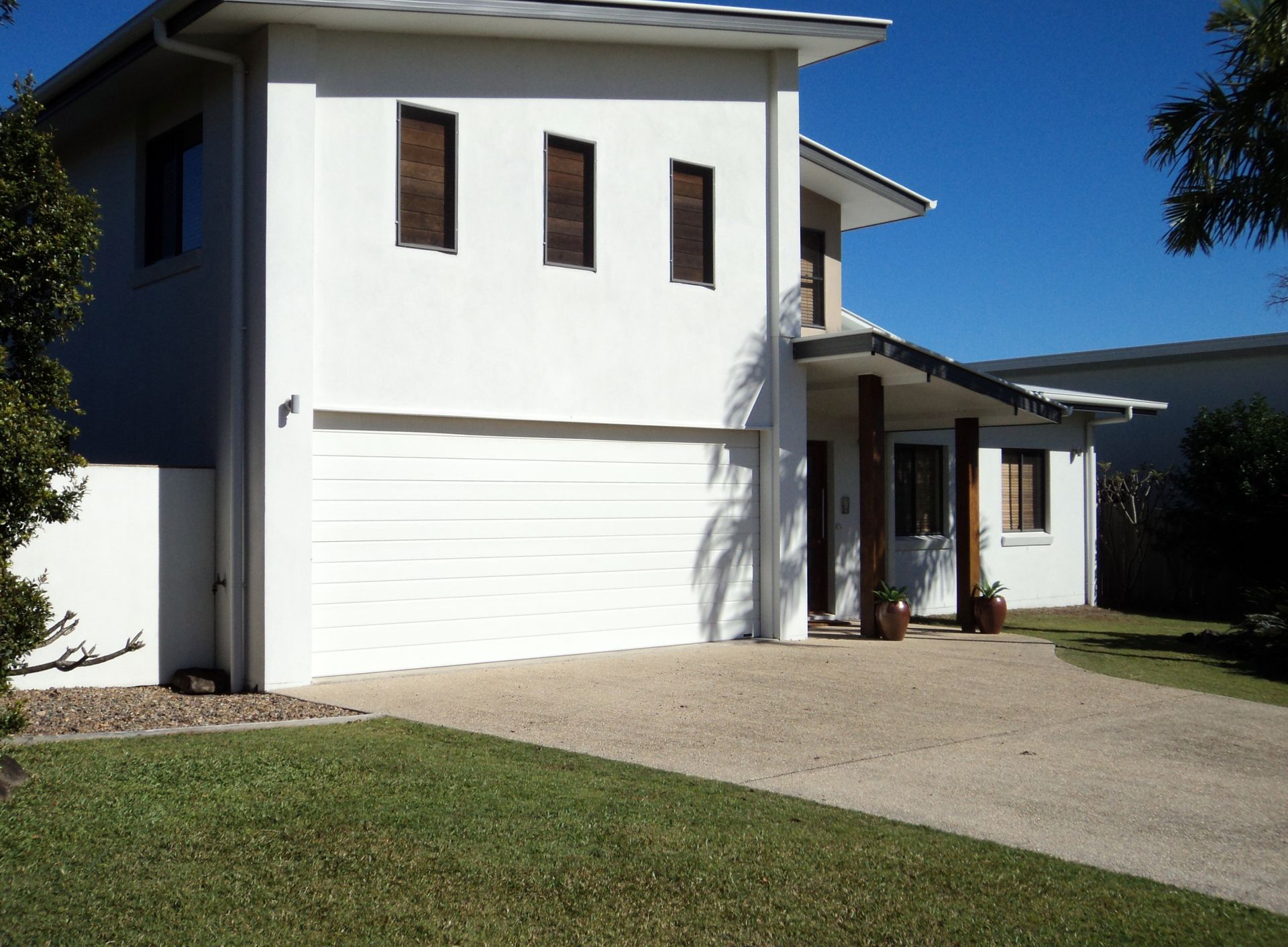 White two-story house with a garage and a driveway on a sunny day — Coastal Auto Doors & Gates In Palmwoods, QLD