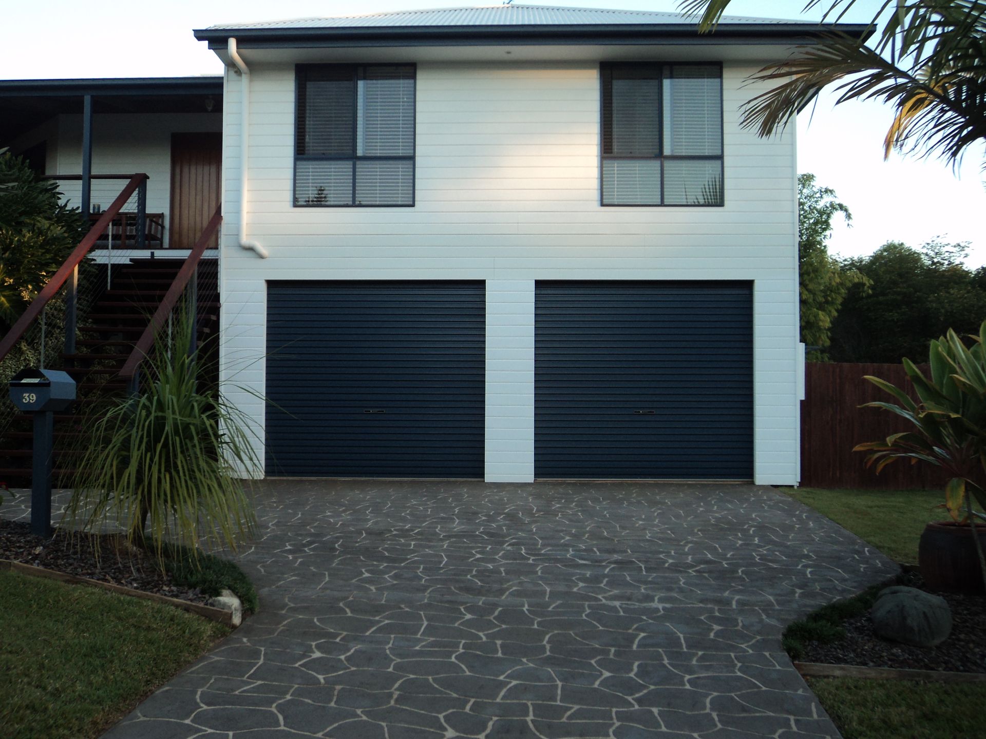 A Black Garage Door On the Front Of A Modern Home — Coastal Auto Doors & Gates In Palmwoods, QLD