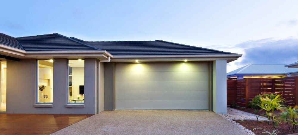 A house with a garage door and a driveway in front of it.