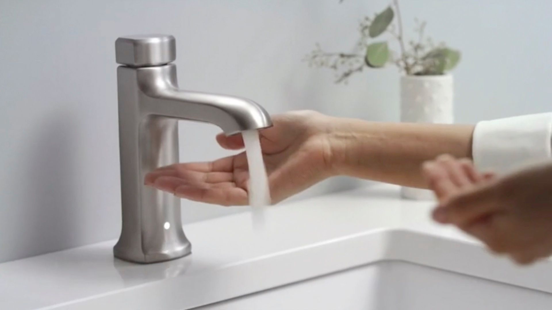 A person is washing their hands in a bathroom sink.