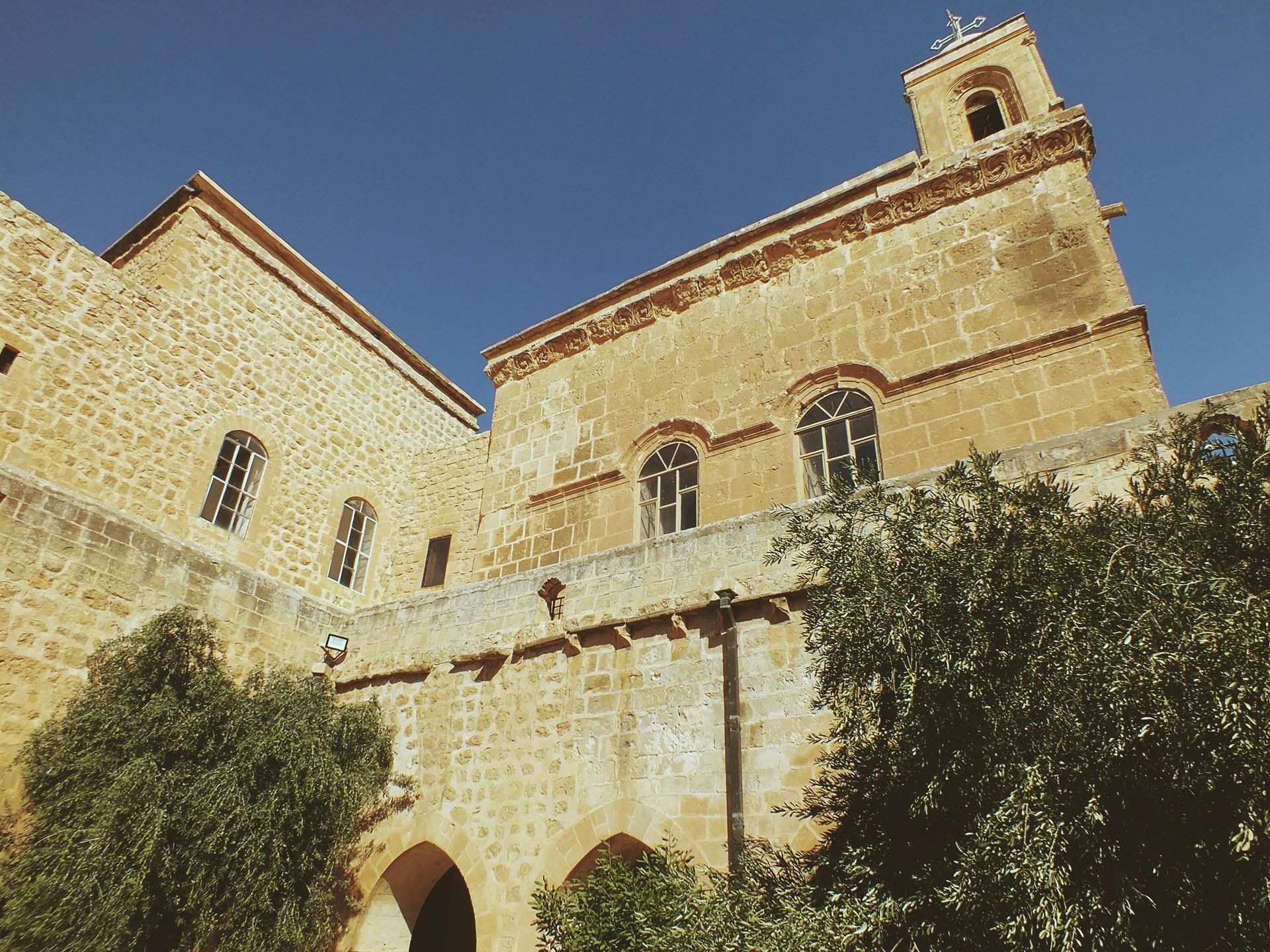 Stone building with arches and windows, under a clear blue sky.
