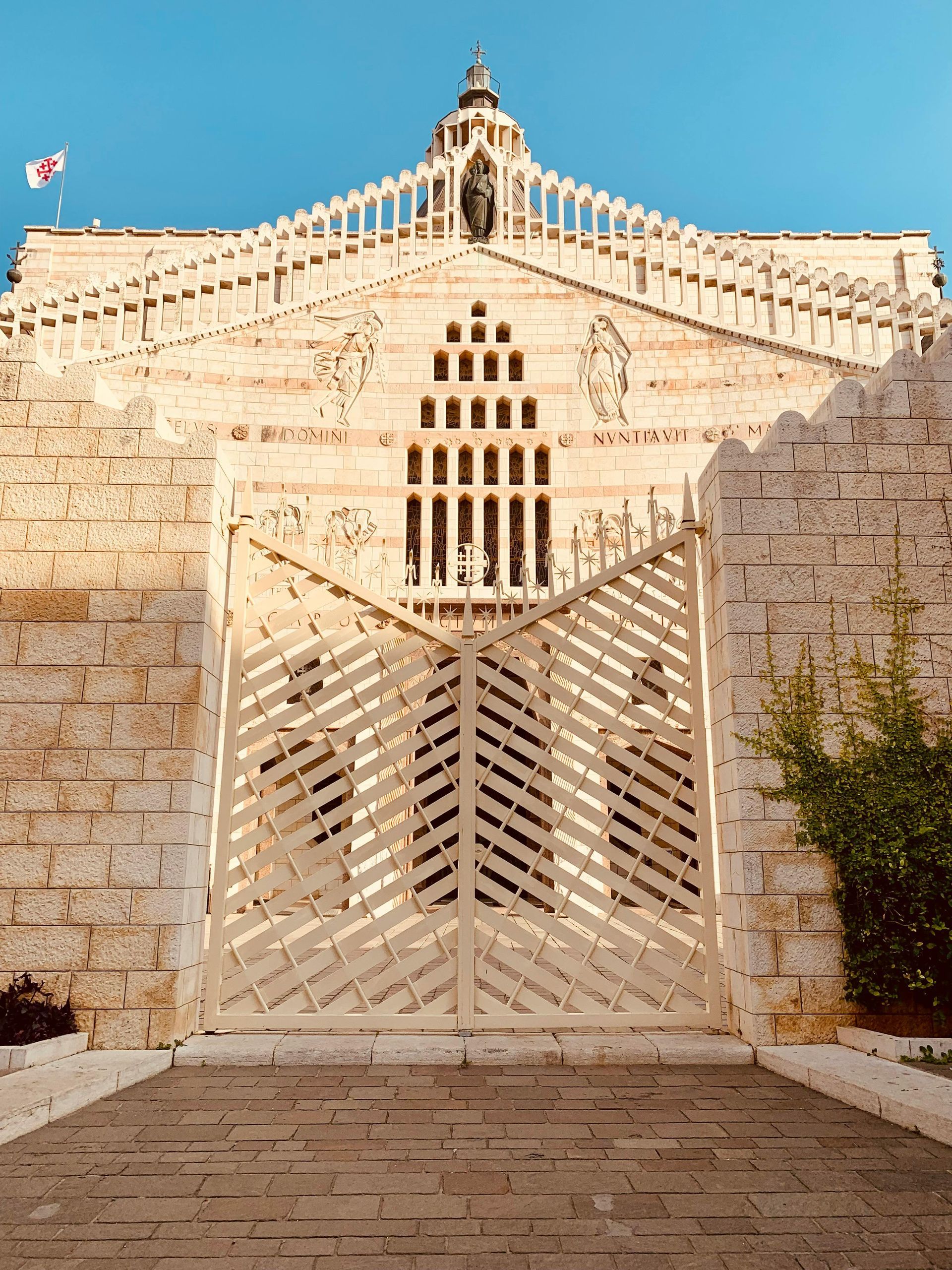 White stone Basilica with ornate gate and carved facade.