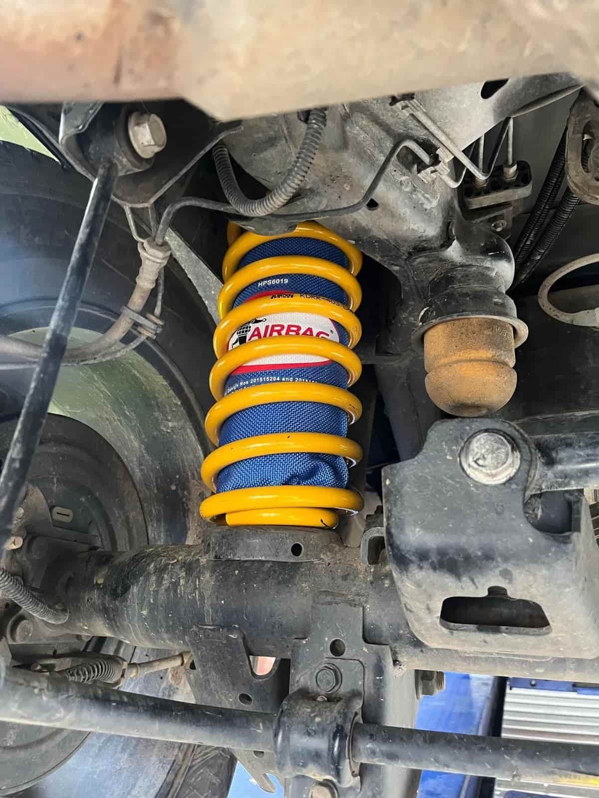 Yellow and Blue Suspension Spring in a Vehicle's Undercarriage — Burcher EFI & Service Centre in Orange, NSW