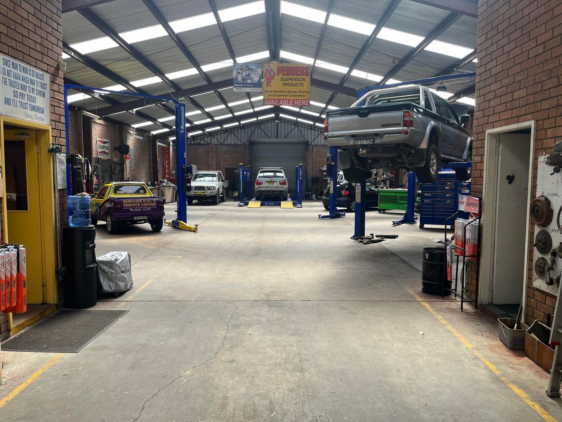 Inside Auto Repair Shop: Cars on Lifts, Tools, Concrete Floor, Brick Walls — Burcher EFI & Service Centre in Orange, NSW