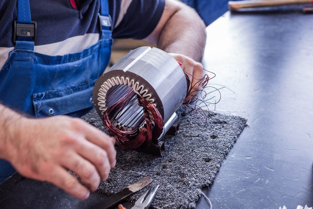 Man Working on an Electric Motor, Wires Visible, Blue Overalls, on a Workbench — Burcher EFI & Service Centre in Orange, NSW