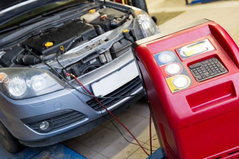 A Silver Car With Its Hood Open Connected to a Red Ac Recharge Machine — Burcher EFI & Service Centre in Orange, NSW