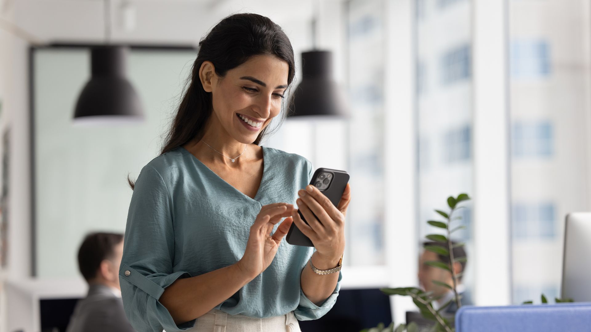Woman holding a phone in an office.