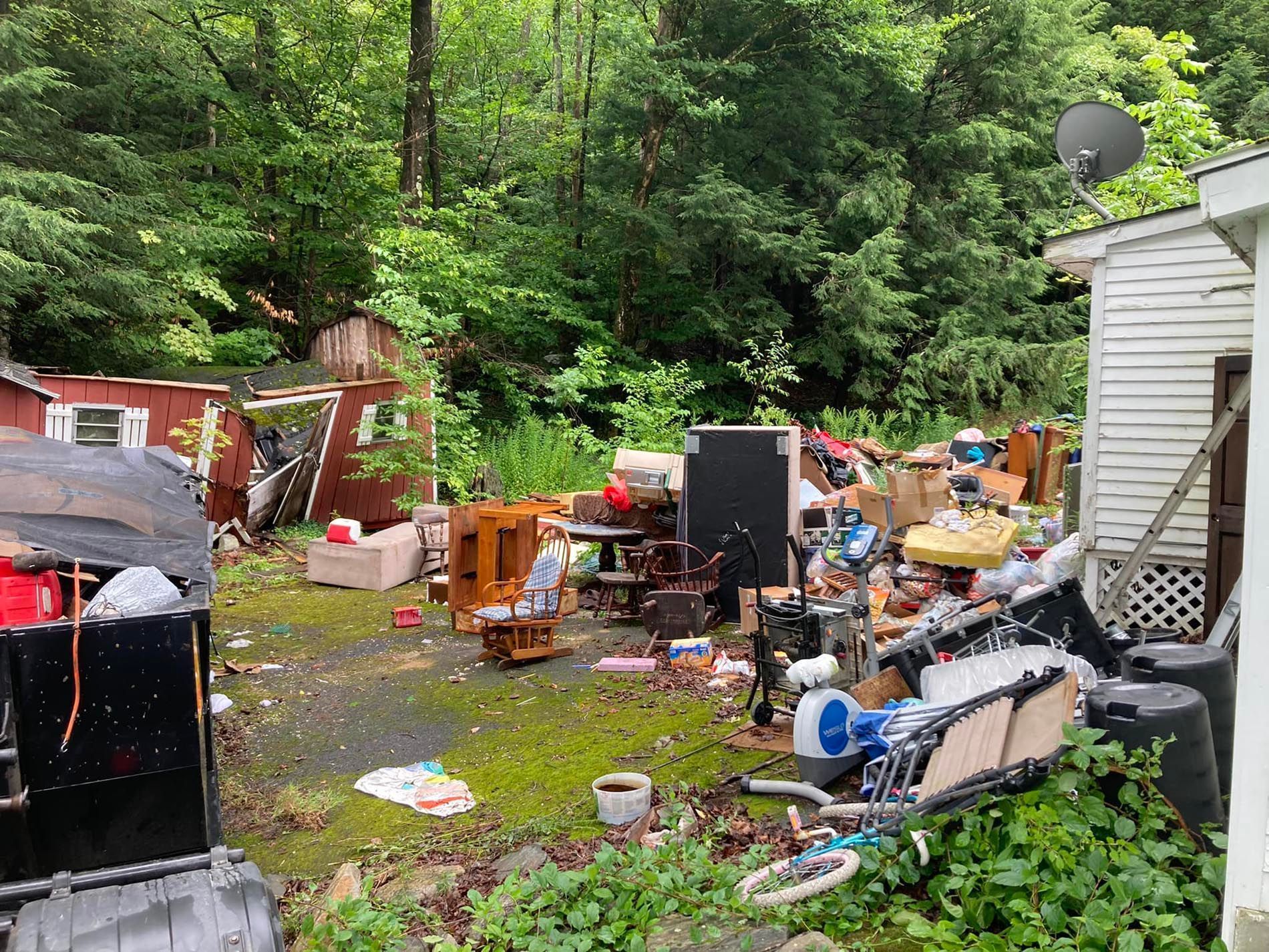 Backyard cluttered with debris, furniture, and various objects.