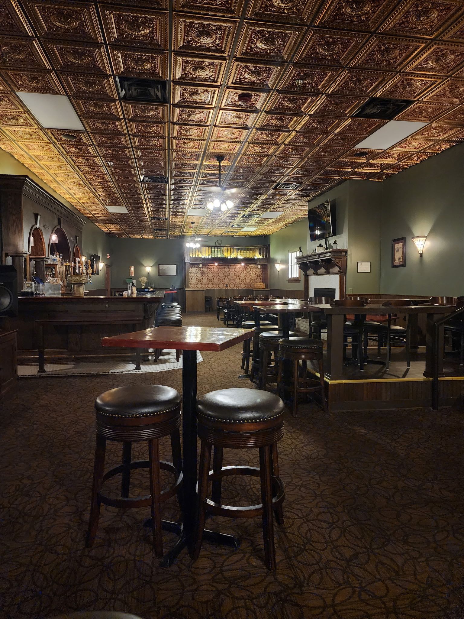 A bar with tables and stools and a copper ceiling