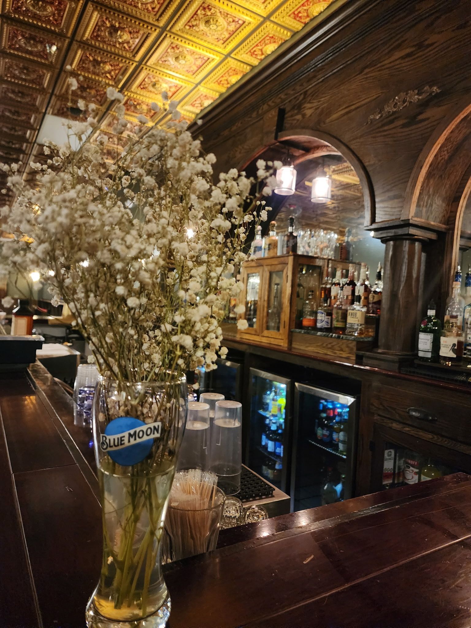 A vase of baby 's breath flowers is sitting on a bar.