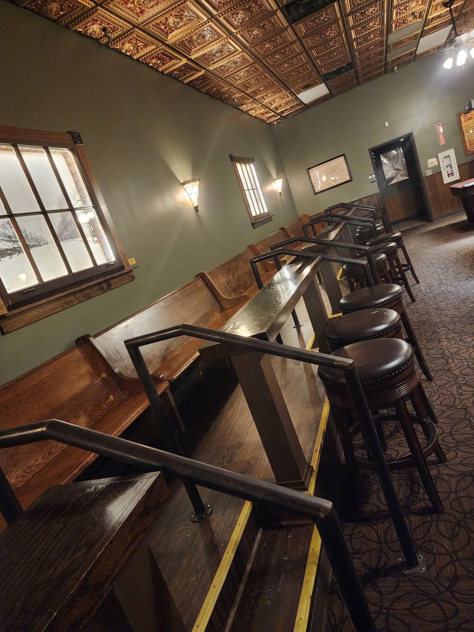 A bar with stools and tables in a restaurant.