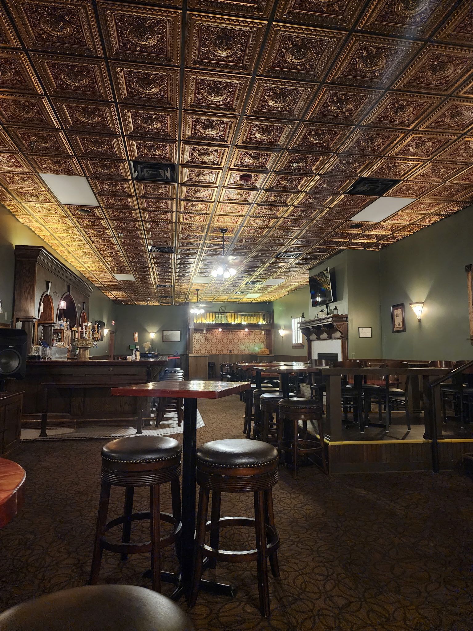 A bar with tables and stools and a copper ceiling