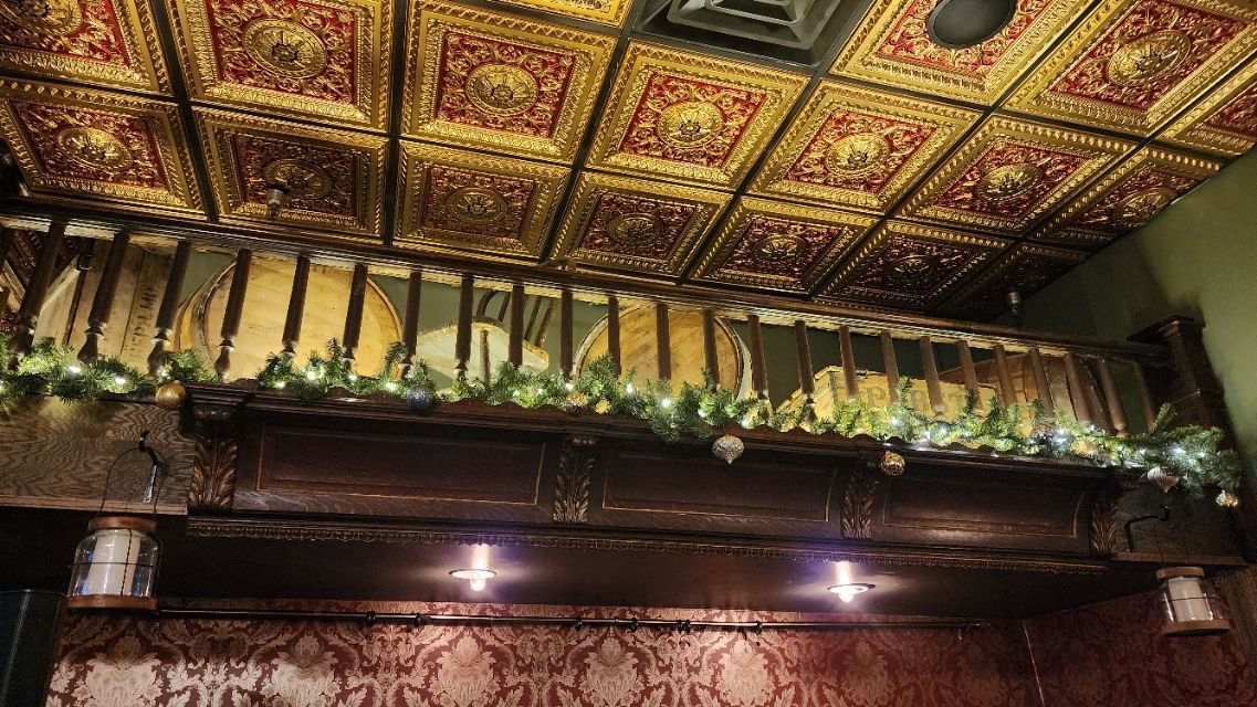 The ceiling of a room with a gold tile ceiling and a wooden railing.