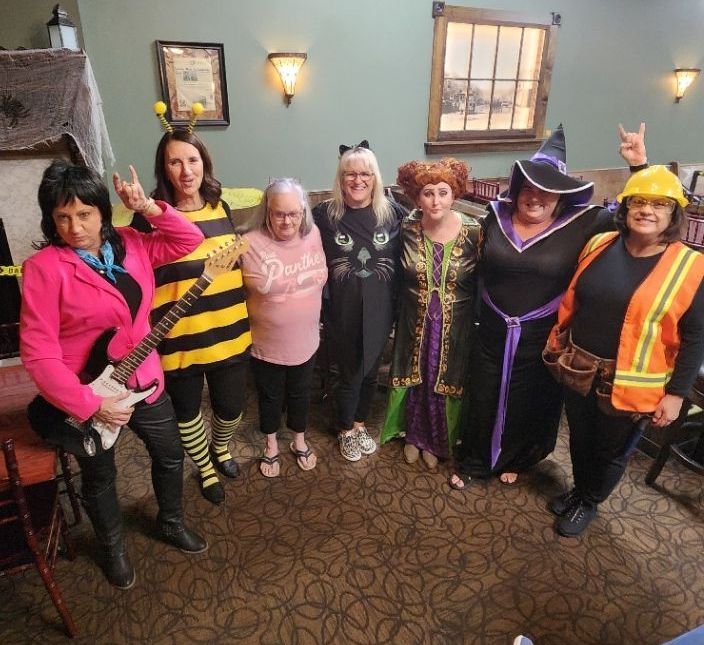 A group of women dressed in halloween costumes are posing for a picture