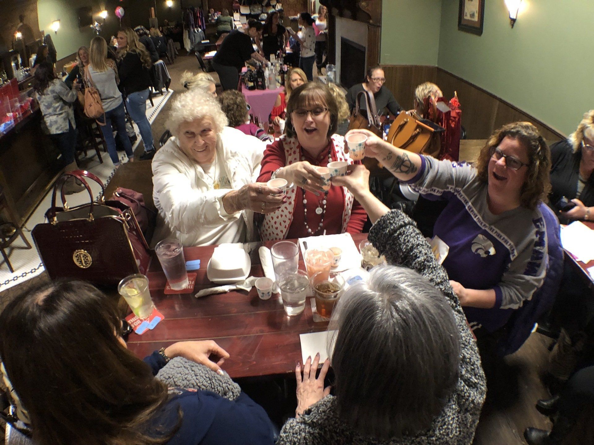 A group of women are sitting around a table toasting