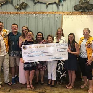 A group of people are standing next to each other holding a large check.