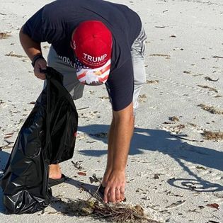 A man on the beach picking up trash