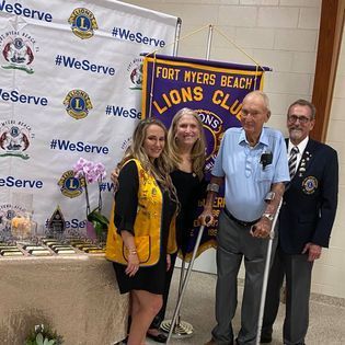 A group of people standing in front of a banner that says fort myers beach lions club