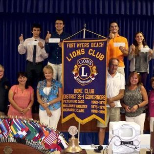 A group of people standing around a banner that says fort myers beach lions club