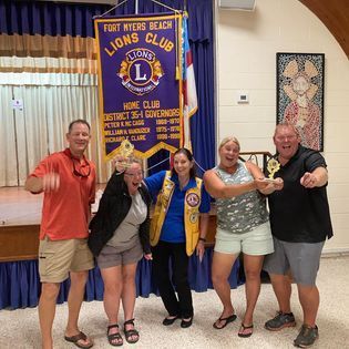 A group of people standing in front of a lions club banner
