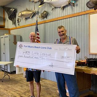 Two men are holding a large check in a room.