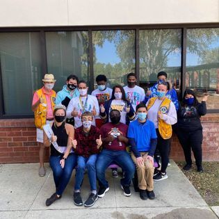 A group of people wearing face masks are posing for a picture in front of a building.