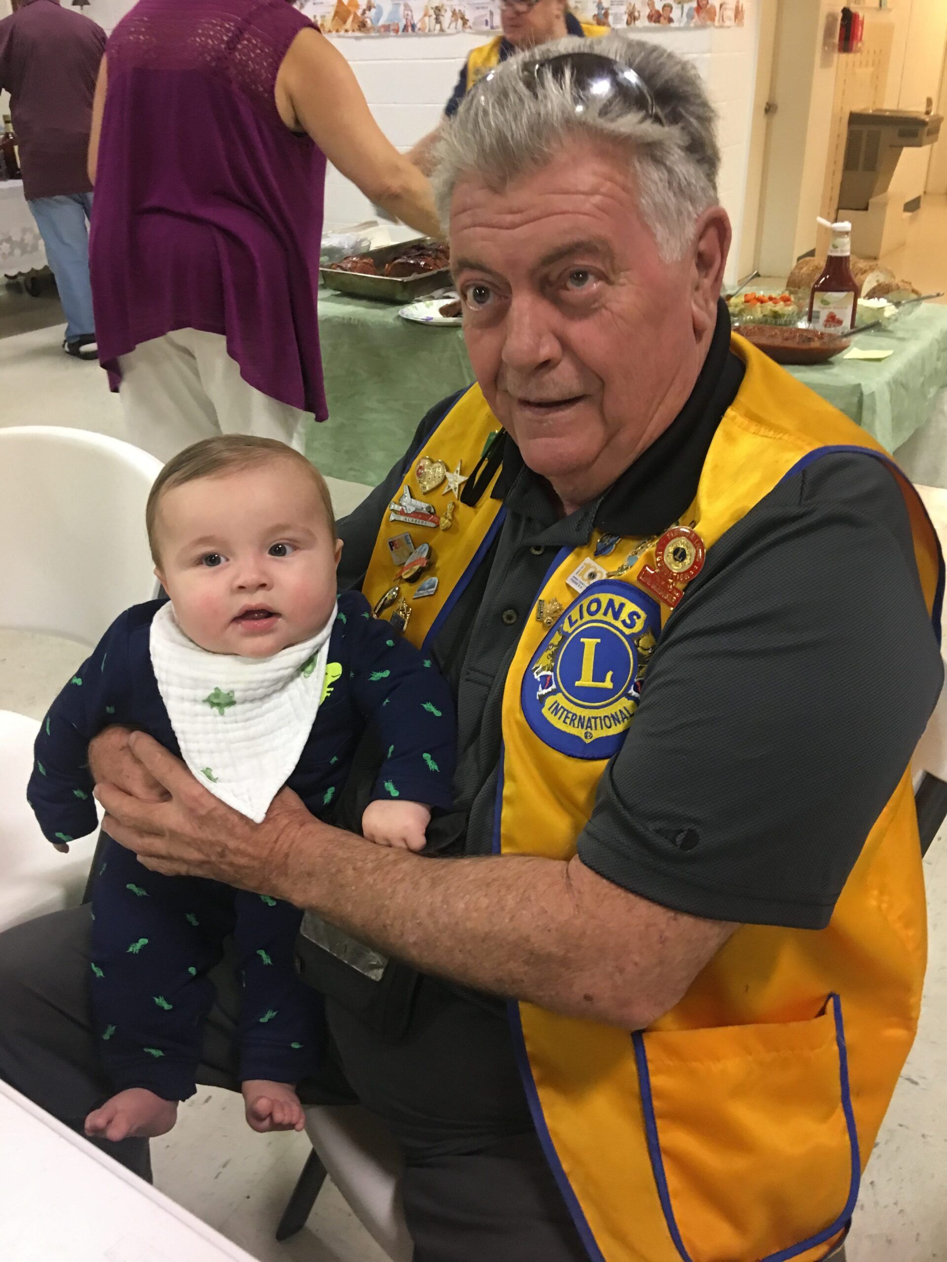 A man in a lions vest is holding a baby