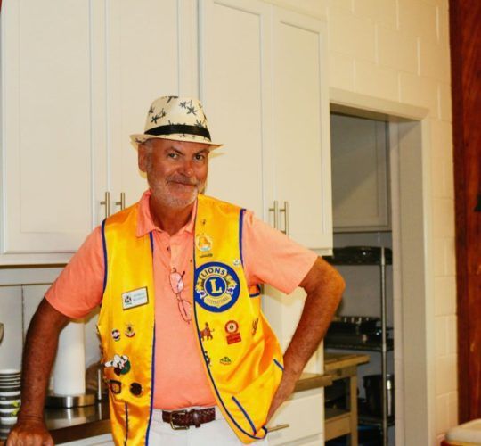 A man wearing a hat and a yellow vest with the letter l on it
