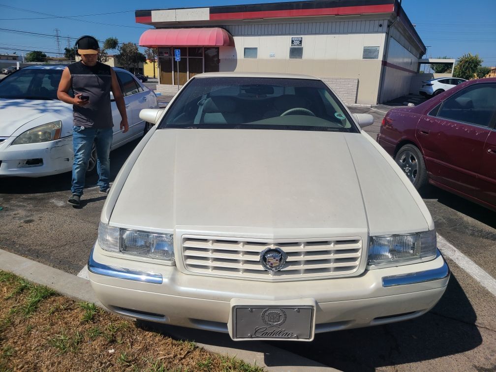 A man is standing next to a white car in a parking lot